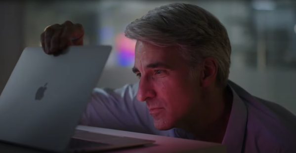 Craig Federighi looking wistfully at a Mac laptop in a darkened room