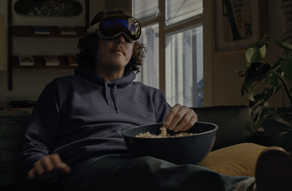 a guy sitting on his couch with a bowl of popcorn with his Apple Vision Pro headset on