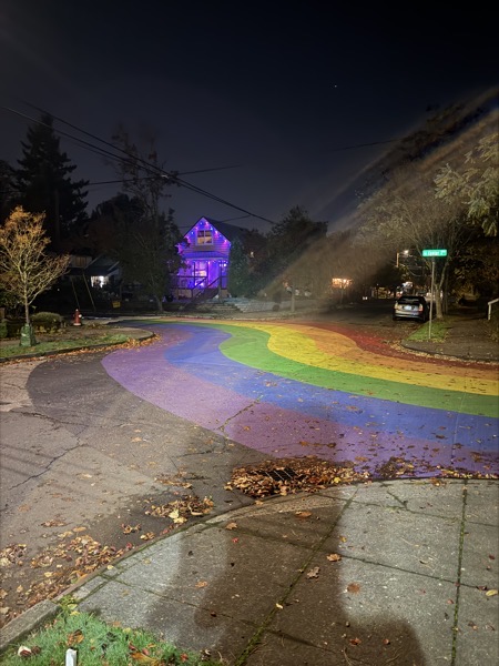 a neighborhood intersection where the street is painted with a rainbow